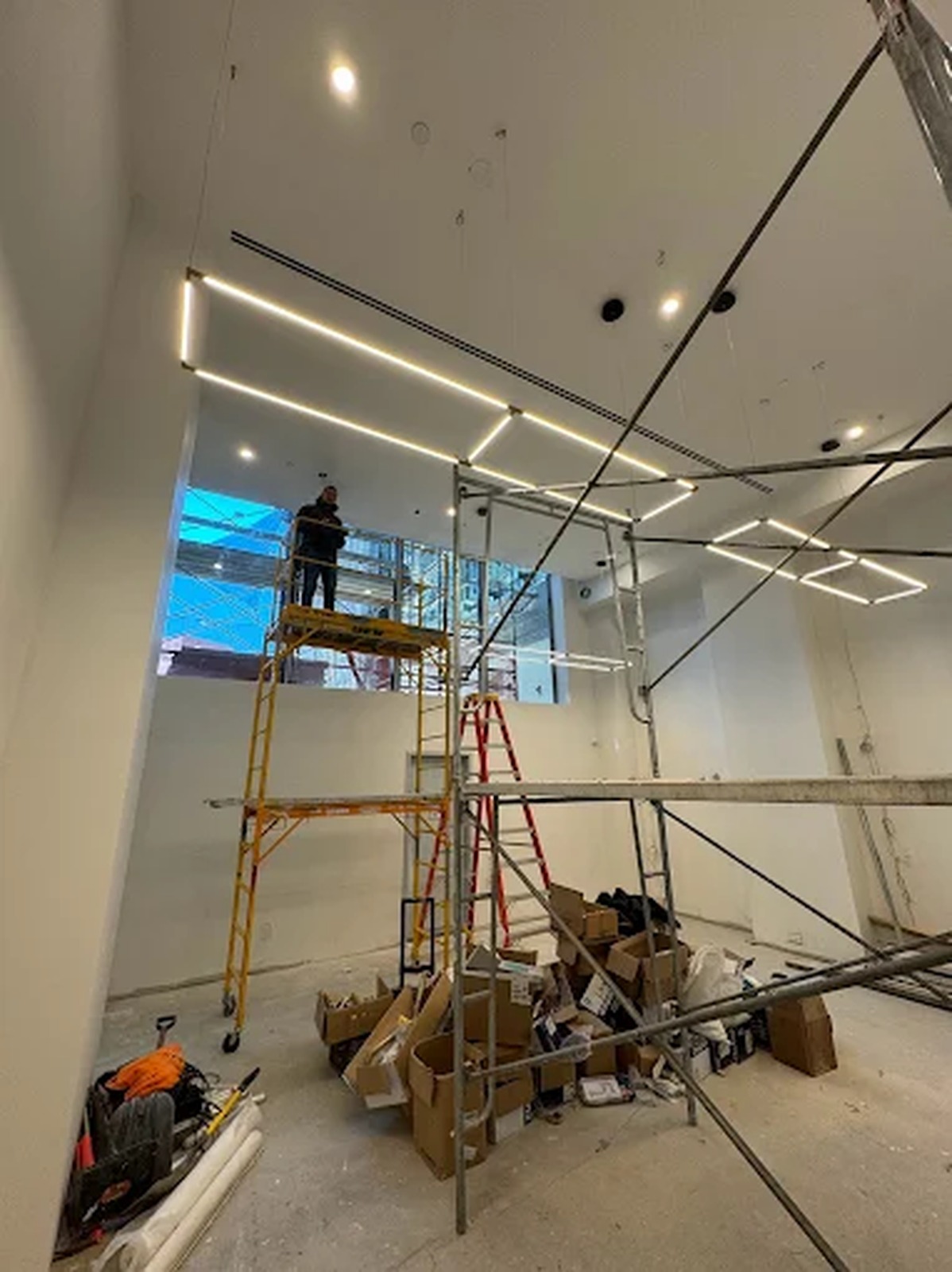 Linear LED lighting installed from scaffolding in a double-height space