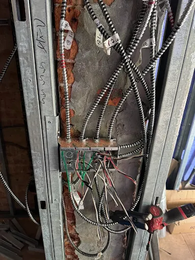 Labeled BX branch circuits pulled into a riser wall during a rough-in