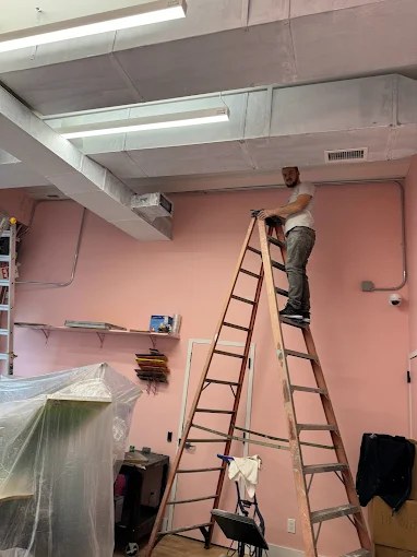 Electrician installing linear fixtures in a commercial retail space